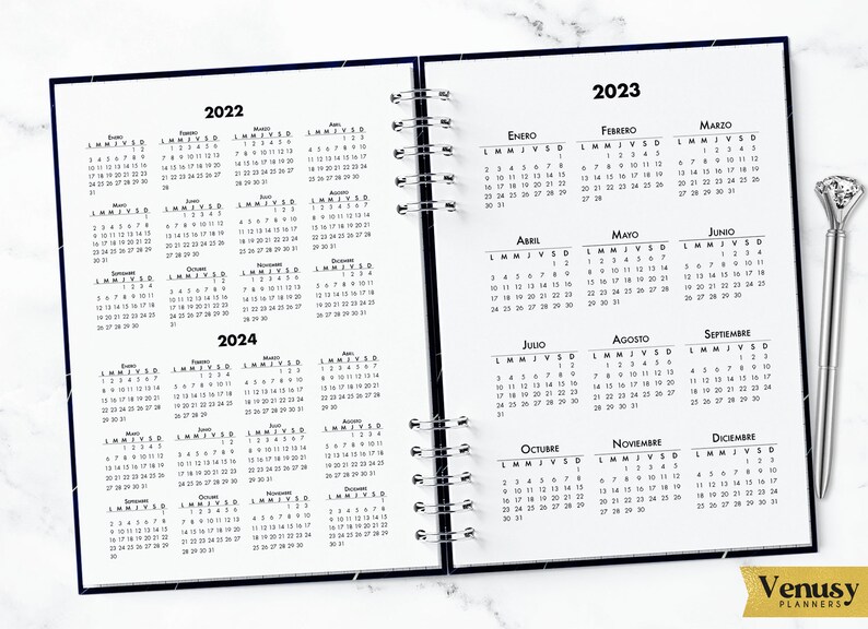 May include: A black and white calendar planner with a galaxy design. The planner includes the months of January through December for the years 2022, 2023, and 2024. The planner is open to the months of July, August, and September of 2023.