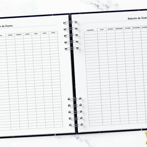 May include: A black and white planner with two pages open. The left page has a table with the months of the year listed across the top and the word "Concepto" at the top of the first column. The right page has a table with the months of the year from June to December listed across the top and the word "Concepto" at the top of the first column. The planner has a spiral binding.
