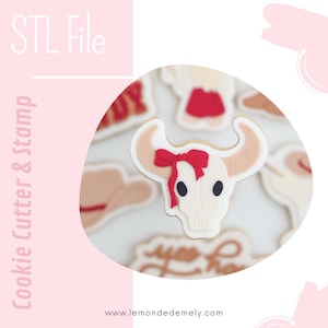Peut inclure: Un biscuit décoré en forme de crâne de taureau avec un nœud rouge. Le biscuit est blanc avec des orbites noires et des cornes beiges. D'autres biscuits en arrière-plan incluent un chapeau de cow-boy et une jupe rouge. Le texte sur l'image dit "STL File" et "Cookie Cutter & Stamp".