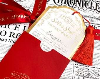 May include: A Christmas gift set with a red tag reading "Official Santa's Sleigh Delivery Receipt" in gold lettering. The tag is attached to a red tassel and is placed in a red envelope. The gift is wrapped in newspaper-style paper.