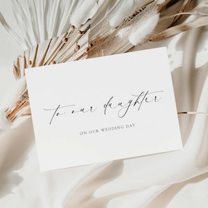 May include: A white card with black calligraphy that reads "To our daughter on our wedding day".
