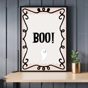May include: A black framed printable with a pink background and a white ghost. The text "BOO!" is in black bold letters.