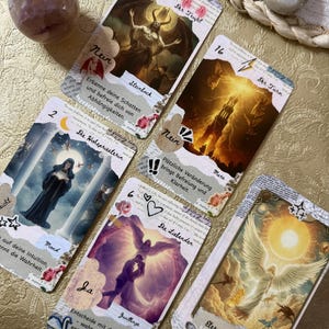 May include: A collection of tarot cards with various illustrations and German text. The cards feature images of angels, demons, and other symbolic figures. The cards are arranged on a gold-colored surface, with a crystal ball and a stone in the background.