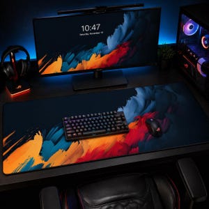Può includere: Configurazione di gioco con tastiera e mouse neri su un ampio tappetino per mouse con un design astratto colorato. Il monitor mostra l'ora e la data. Sono visibili anche cuffie e un case per computer.