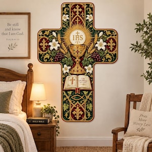May include: A cross-shaped wall hanging featuring a central golden chalice, a white host with the letters IHS, and an open book labeled The Bread of Life. The design includes white lilies, wheat stalks, grapes, and gold fleur-de-lis on a dark background.