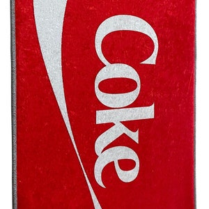May include: Red doormat with a white Coca-Cola logo and wave design.