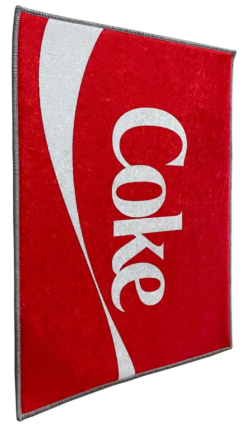 May include: Red doormat with a white Coca-Cola logo and wave design.