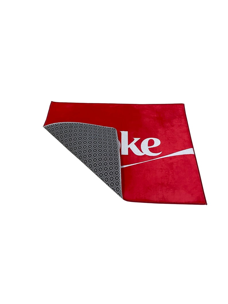 May include: Red doormat with the word "Coke" in white lettering. The back of the doormat is gray with a diamond pattern.