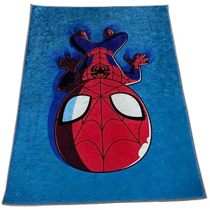 May include: A blue fleece blanket with a cartoon image of Spiderman hanging upside down. The Spiderman character is red and black with a white spider symbol on his chest.