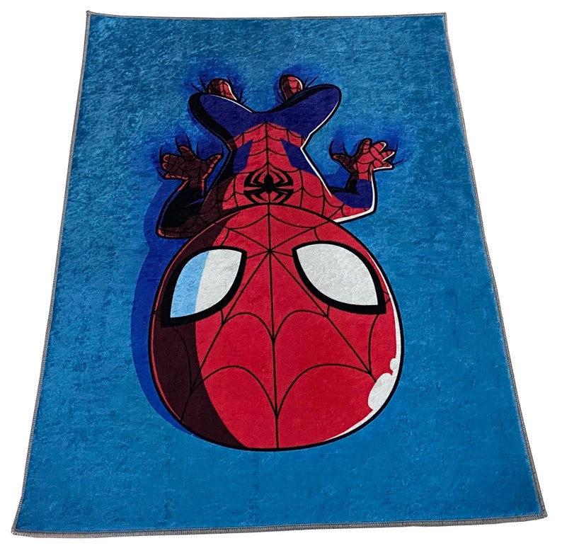 May include: A blue fleece blanket with a cartoon image of Spiderman hanging upside down. The Spiderman character is red and black with a white spider symbol on his chest.