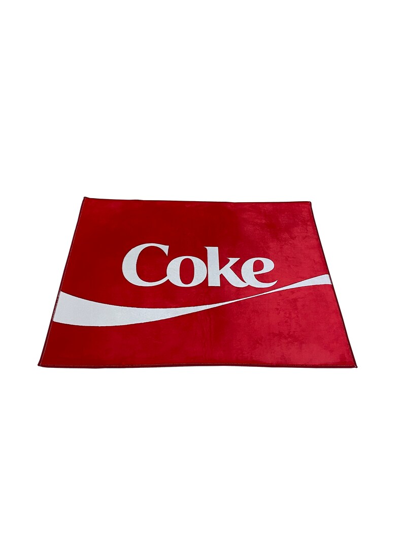 May include: Red rectangular rug with a white Coca-Cola logo and a white wave design.