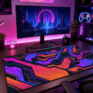 Può includere: Un ampio tappetino per mouse da gioco rettangolare con un vivace design geometrico a circuito stampato nei toni del viola, arancione e blu. Un mouse nero poggia sul tappetino, che si trova su una scrivania con un monitor e una tastiera.
