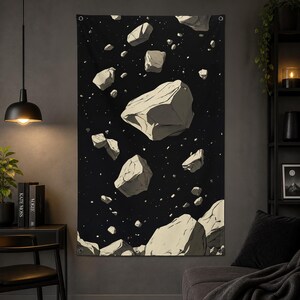 Pode incluir: Uma tapeçaria de parede com um fundo preto e rochas flutuantes cinza claro de forma irregular. Pontos brancos, semelhantes a estrelas, estão espalhados pela cena. A obra de arte evoca um tema cósmico ou espacial.