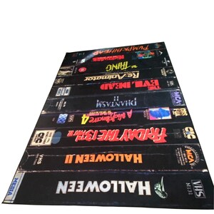 May include: A stack of VHS tapes featuring horror movie titles including Halloween, Friday the 13th, A Nightmare on Elm Street, Phantasm, Evil Dead, Re-Animator, The Thing, and Pumpkinhead.