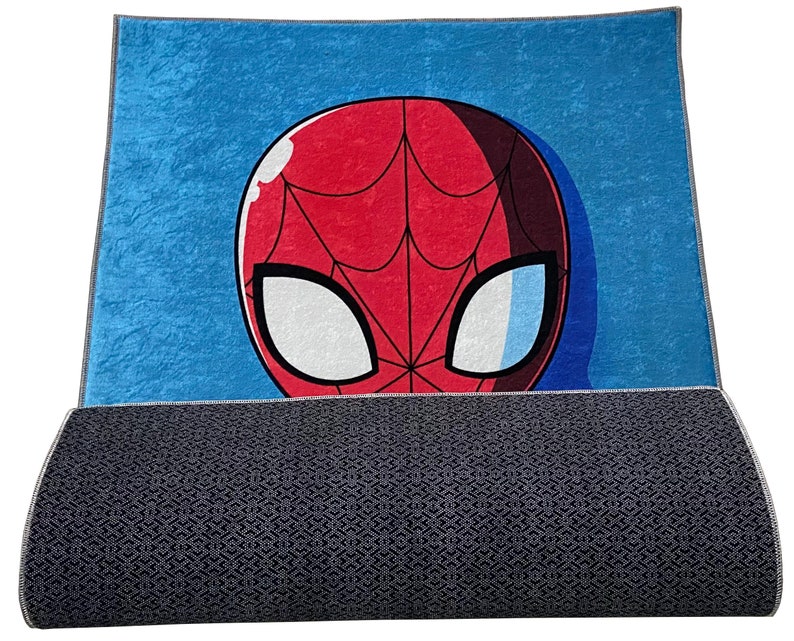 May include: A blue and red rug with a cartoon image of Spider-Man's face. The rug has a gray backing.