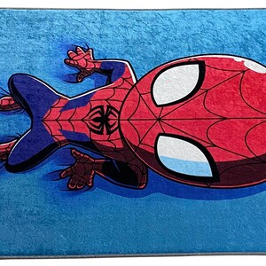 May include: A blue rug with a cartoon image of Spiderman in a red and blue suit. Spiderman is lying on his back with his arms and legs outstretched.