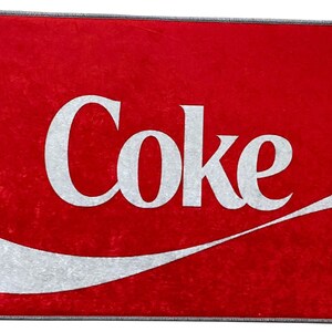 May include: Red doormat with a white wave design and the word "Coke" in white lettering.