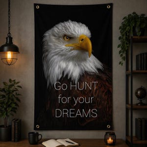 May include: A black wall tapestry featuring a detailed image of a bald eagle with white feathers, a yellow beak, and intense gaze. The text "Go HUNT for your DREAMS" is printed in white. The tapestry has metal grommets for hanging.