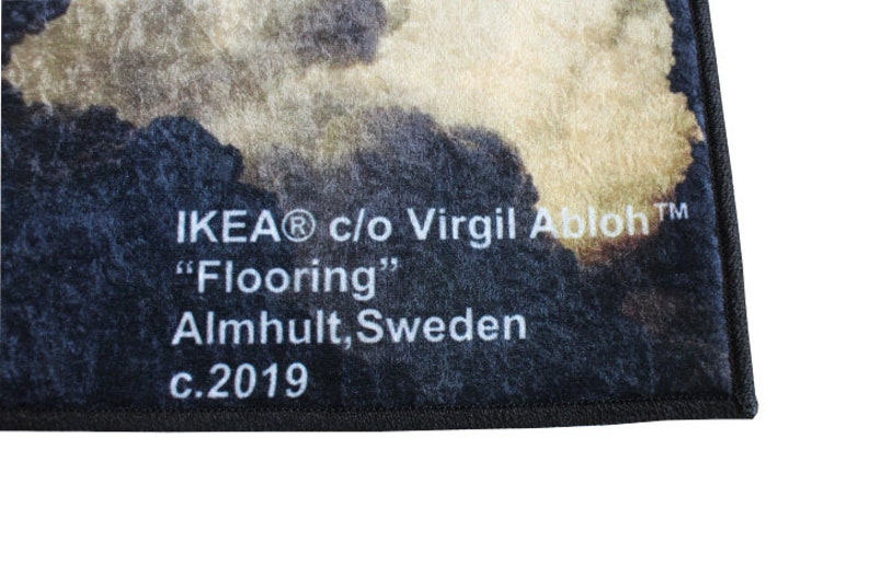 Pu&ograve; includere: Primo piano di un tappeto nero e bianco con un motivo sbiadito. Il tappeto ha un bordo nero e testo bianco che recita "IKEA&reg; c/o Virgil Abloh&trade; "Flooring" Almhuult, Svezia c.2019"