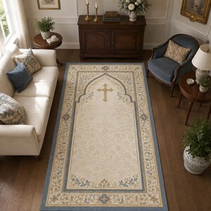Puede incluir: Una alfombra de oración rectangular con un centro color crema y un emblema de cruz dorada, enmarcada por un borde arqueado en tonos azul, dorado y beige, decorada con patrones florales y motivos geométricos en las esquinas.