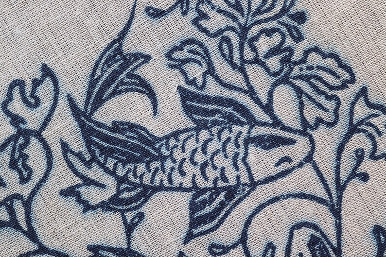Closeup of linocut art print in indigo ink on natural irish linen featuring swimming koi fish and William Morris inspired botanical designs. Framed in a frame package. 8x10 inches.