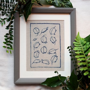 May include: A framed embroidery piece with a white background and blue stitching. The embroidery depicts a pattern of 16 stylized leaves.