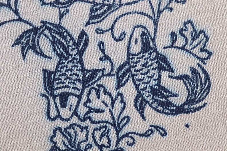 Closeup of linocut art print in indigo ink on natural irish linen featuring swimming koi fish and William Morris inspired botanical designs. Framed in a frame package. 8x10 inches.
