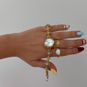 Reloj con dije floral dorado, esfera minimalista, pulsera delicada, estilo de inspiración vintage. imagen 5