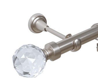 May include: Silver curtain rod with a crystal finial and rings. The rod is mounted to a wall with a bracket.