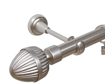 May include: A brushed nickel curtain rod with decorative finials. The rod has a series of rings with clips for hanging curtains. The finial is a rounded, ribbed design. The rod is designed to be mounted on a wall.