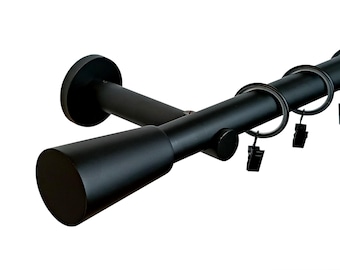 May include: Black metal curtain rod with a cone-shaped finial and a wall mount bracket. The rod has rings and clips for hanging curtains.