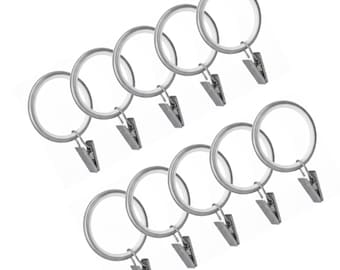 May include: A set of ten silver-colored curtain rings with attached clips. Each ring is circular and made of metal, with a small clip hanging from the bottom. The clips are designed to hold fabric, and the rings are for hanging curtains.