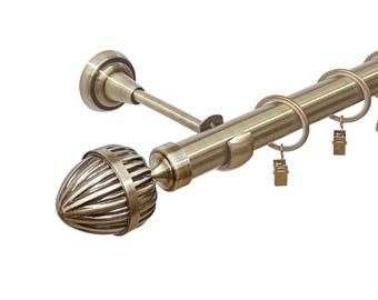 May include: A gold metal curtain rod with a decorative finial and rings. The rod is mounted to a wall and has a bracket on the end.