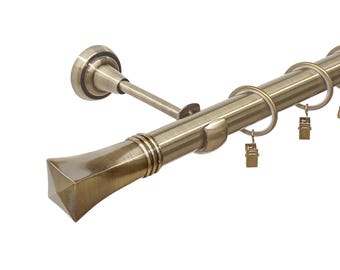 May include: A gold metal curtain rod with a square finial and a decorative bracket. The rod has rings and clips for hanging curtains.