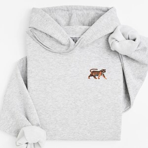 May include: A gray hooded sweatshirt with a small embroidered image of an orange and black tiger on the front.