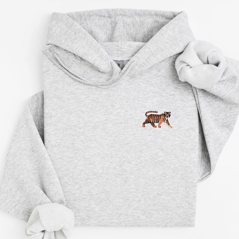 May include: A gray hooded sweatshirt with a small embroidered image of an orange and black tiger on the front.