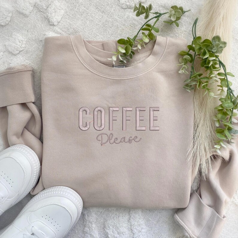 May include: A light beige sweatshirt with the text "COFFEE Please" in pink and white lettering.