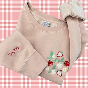 May include: A pale pink sweatshirt with a red embroidered strawberry design and the name "Zoeey Kay" embroidered on the sleeve.