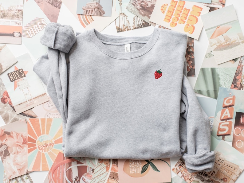 May include: A gray sweatshirt with a small embroidered strawberry on the left chest.