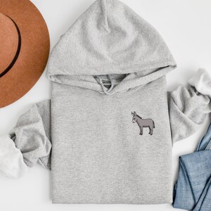 Puede incluir: Una sudadera con capucha gris con una peque&ntilde;a imagen bordada de un burro gris en la parte delantera.