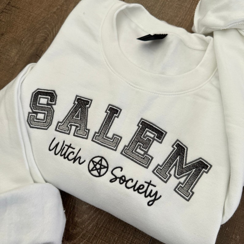 May include: White sweatshirt with black embroidered text that reads "SALEM Witch Society" with a pentagram symbol.