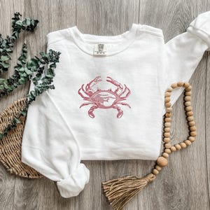 K&ouml;nnte beinhalten: Wei&szlig;es Sweatshirt mit rotem Krabbenmuster. Die Krabbengrafik ist auf der Vorderseite des lang&auml;rmeligen Oberteils aufgedruckt. Das Sweatshirt besteht aus weichem Material und eignet sich f&uuml;r den Freizeitgebrauch.