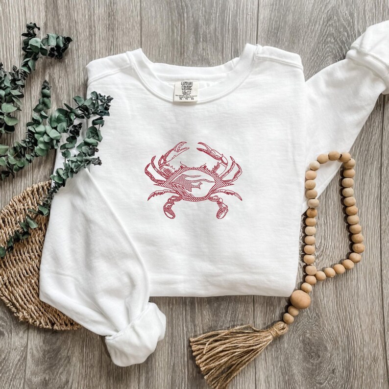 K&ouml;nnte beinhalten: Wei&szlig;es Sweatshirt mit rotem Krabbenmuster. Die Krabbengrafik ist auf der Vorderseite des lang&auml;rmeligen Oberteils aufgedruckt. Das Sweatshirt besteht aus weichem Material und eignet sich f&uuml;r den Freizeitgebrauch.