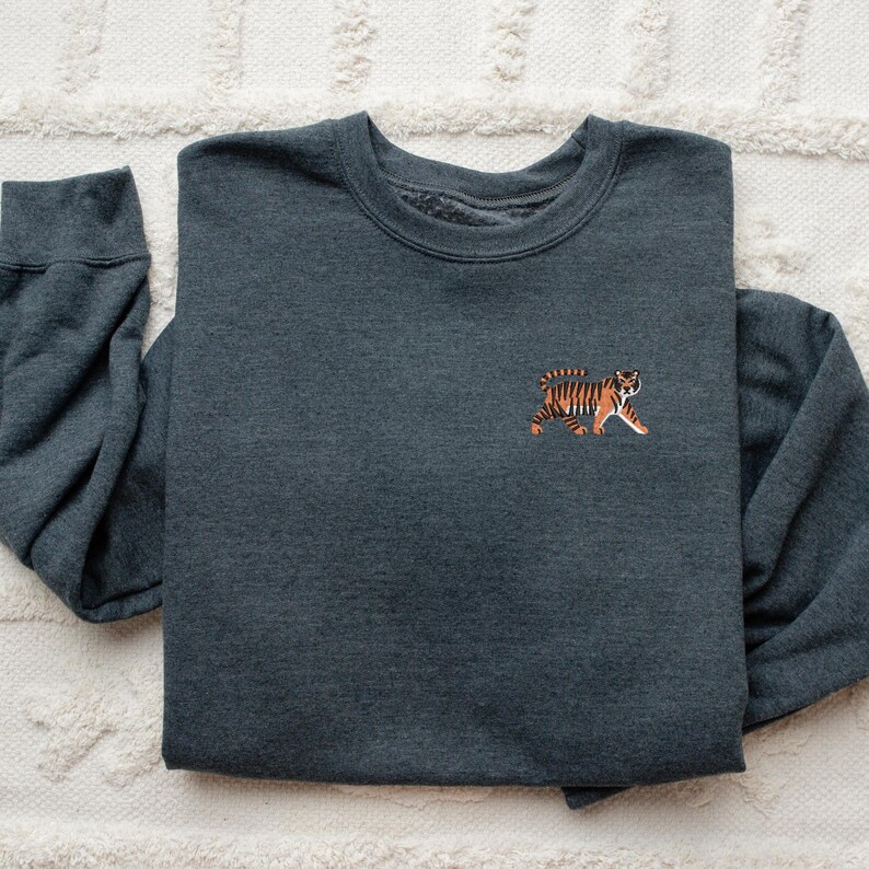 May include: A dark gray sweatshirt with a small embroidered tiger on the left chest. The tiger is orange and black.