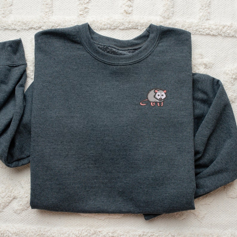 May include: A dark gray sweatshirt with a small embroidered possum on the left chest.
