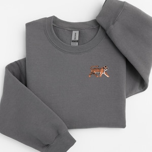 May include: A charcoal gray sweatshirt with a small embroidered tiger on the left chest.