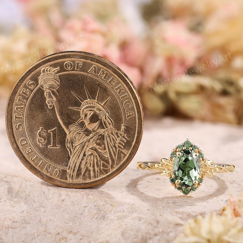 May include: A gold ring with a green gemstone and smaller green stones around it. The ring is next to a United States one-dollar coin.