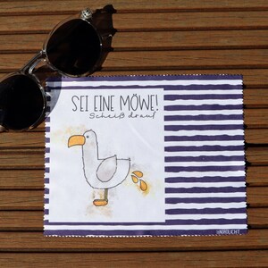 Op de afbeelding: Een witte microvezel schoonmaakdoek met blauwe en witte strepen. De doek heeft een cartoon zeemeeuw met de tekst "Sei eine M&ouml;we! Schei&szlig; drauf" en het woord "NORDLICHT" in de rechterbenedenhoek.