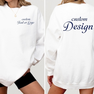May include: A white long-sleeve crewneck sweatshirt featuring dark blue text. The front displays the words custom Text or Logo on the left chest. The back features the words custom Design in a large, prominent script font across the center.