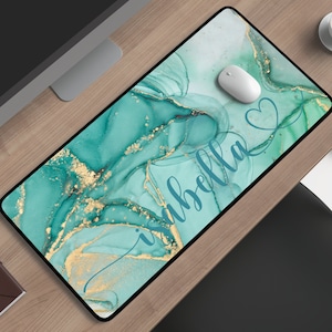 May include: A teal and gold marble-patterned mousepad with the name "Isabella" written in cursive script. A white computer mouse is on the mousepad.